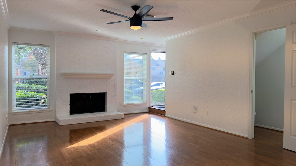 unfurnished living room with dark hardwood / wood-style floors, ornamental molding, a fireplace, and a wealth of natural light