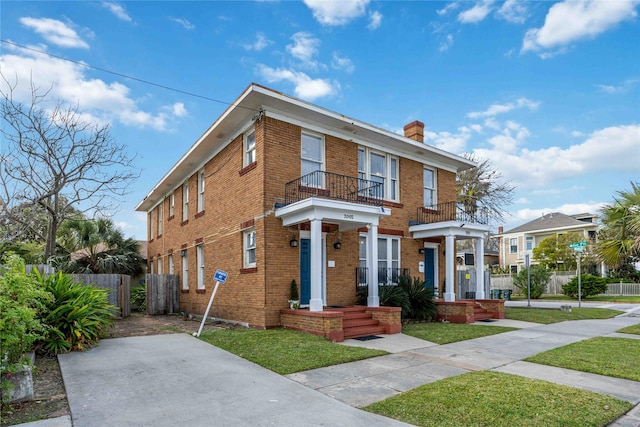 view of front of house with a balcony and a front lawn