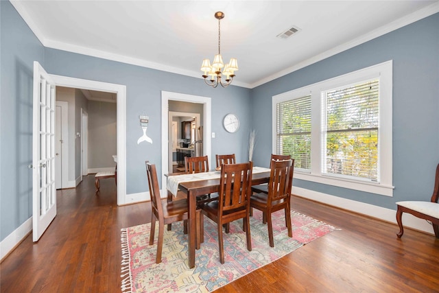 dining space featuring dark hardwood / wood-style flooring, ornamental molding, french doors, and an inviting chandelier