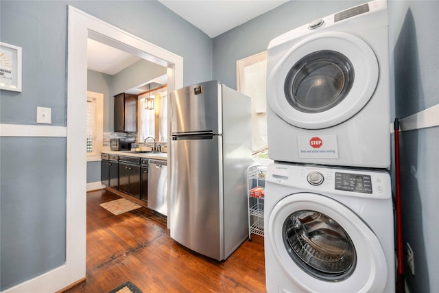 laundry area featuring sink, dark wood-type flooring, and stacked washer and clothes dryer