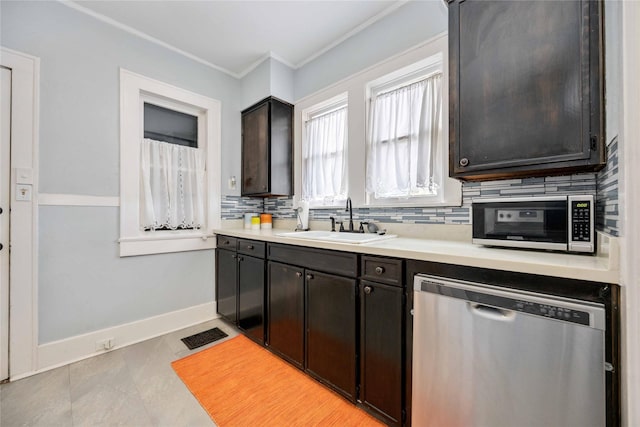 kitchen with appliances with stainless steel finishes, tasteful backsplash, dark brown cabinets, crown molding, and sink