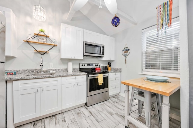 kitchen featuring white cabinets, sink, vaulted ceiling, light wood-type flooring, and stainless steel appliances