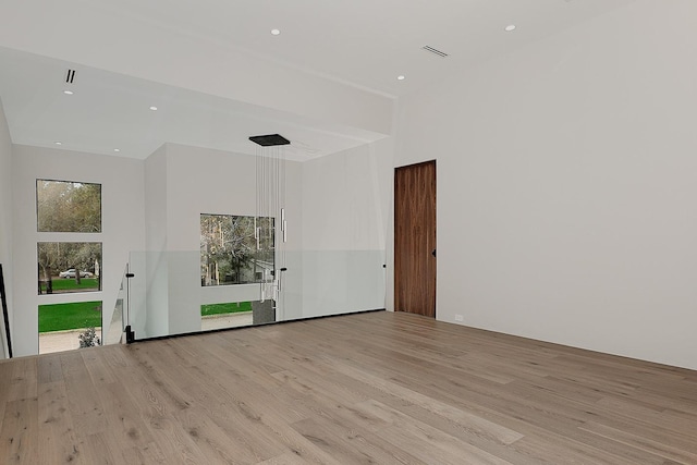 empty room featuring a towering ceiling and light hardwood / wood-style flooring