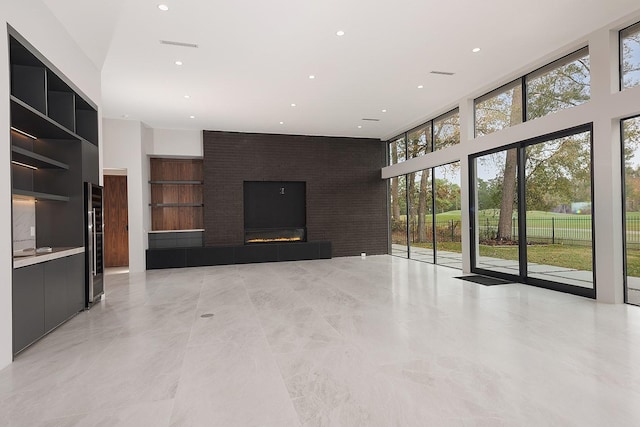 unfurnished living room featuring built in shelves, a towering ceiling, and a tiled fireplace