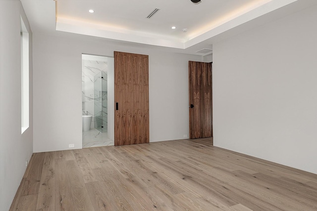 spare room featuring light wood-type flooring and a raised ceiling