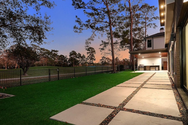 yard at dusk with area for grilling and a patio area