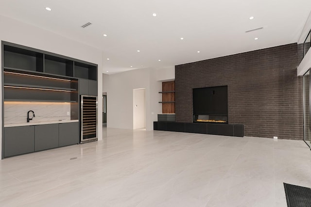 unfurnished living room with brick wall, wine cooler, and a tiled fireplace