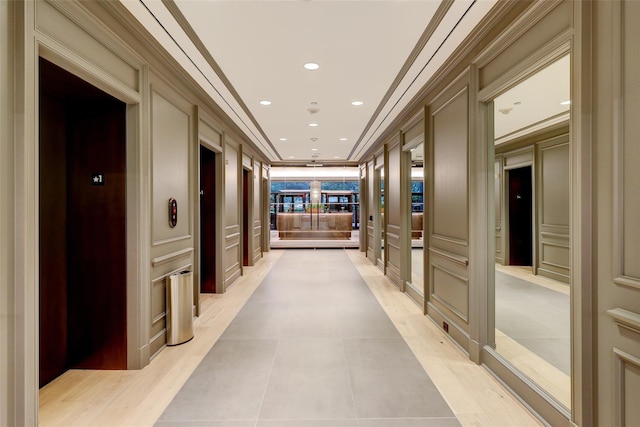 hall with elevator, crown molding, and light tile patterned flooring