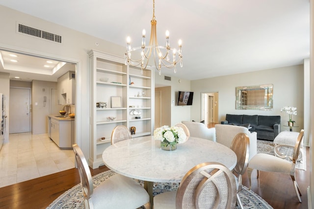 dining space with a notable chandelier, light hardwood / wood-style floors, and sink