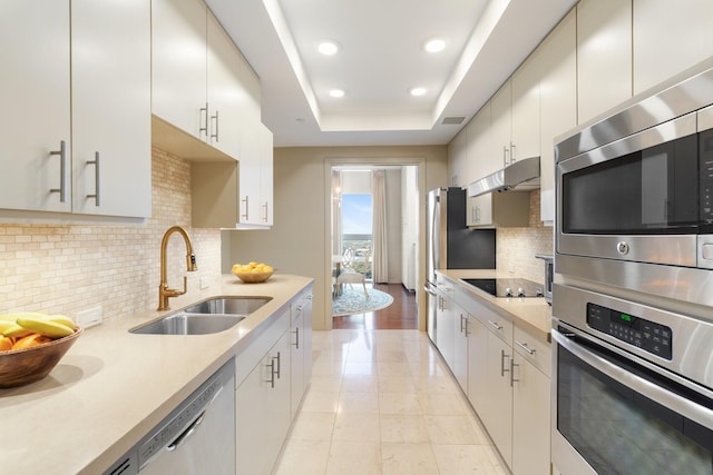 kitchen featuring white cabinetry, sink, a raised ceiling, light tile patterned floors, and appliances with stainless steel finishes