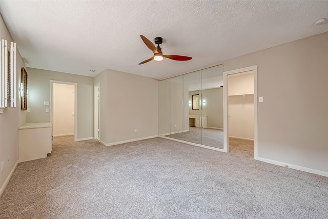 unfurnished bedroom featuring ceiling fan, a closet, light carpet, and a textured ceiling