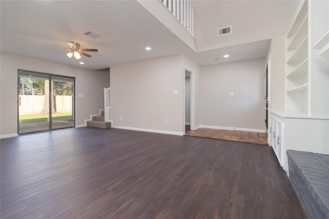 unfurnished living room featuring ceiling fan, dark hardwood / wood-style flooring, a textured ceiling, and built in shelves