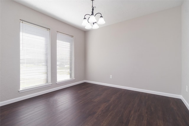 unfurnished room with a chandelier and dark hardwood / wood-style floors