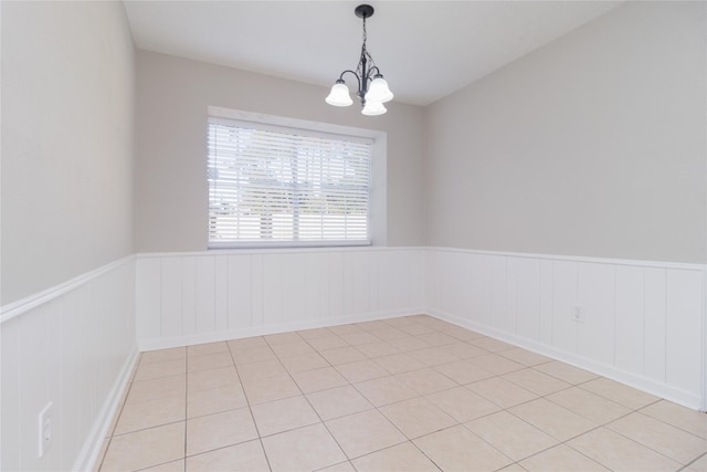 empty room with a notable chandelier and light tile patterned floors