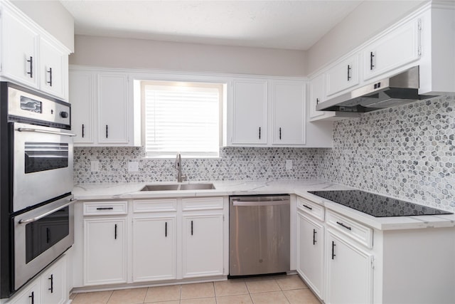 kitchen with white cabinetry, sink, decorative backsplash, light tile patterned floors, and appliances with stainless steel finishes