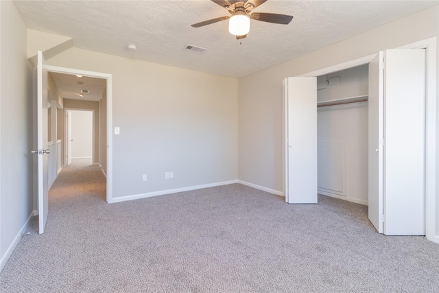 unfurnished bedroom with ceiling fan, light colored carpet, a textured ceiling, and a closet