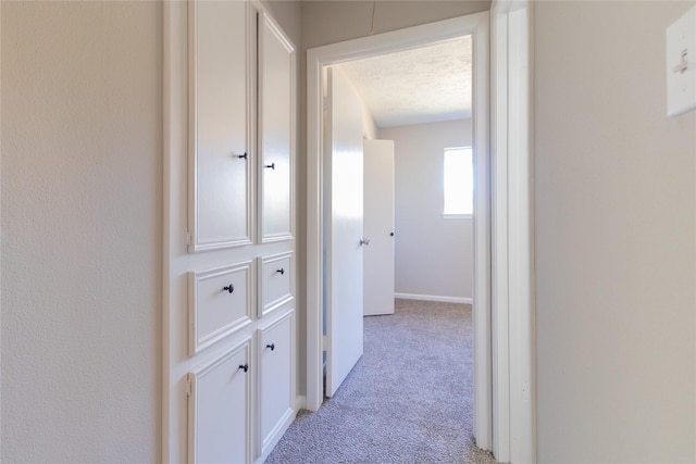 hall with light carpet and a textured ceiling