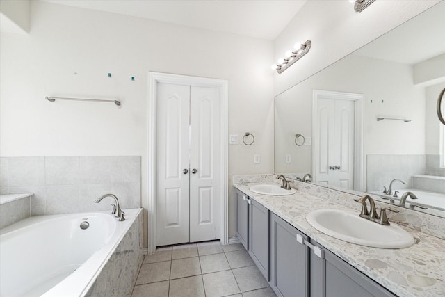 bathroom featuring tiled tub, tile patterned flooring, and vanity