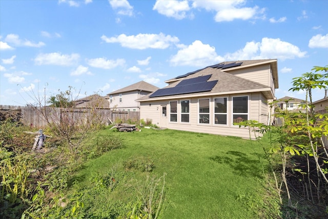 rear view of property featuring solar panels and a lawn