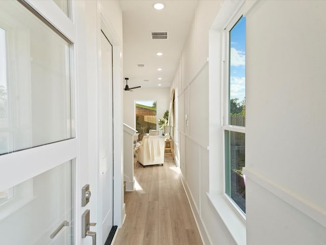 hallway with a healthy amount of sunlight and light hardwood / wood-style flooring