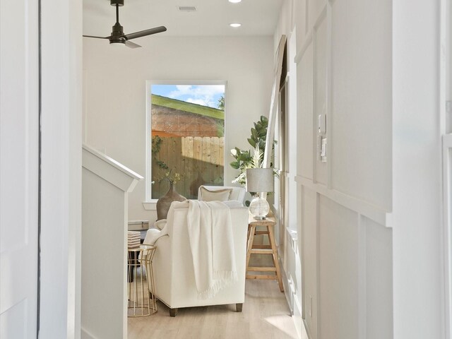 sitting room with ceiling fan and light wood-type flooring