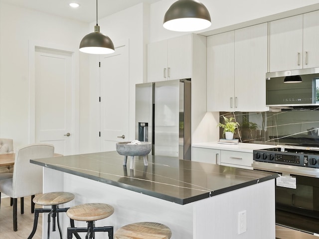 kitchen with decorative light fixtures, decorative backsplash, appliances with stainless steel finishes, and a breakfast bar area