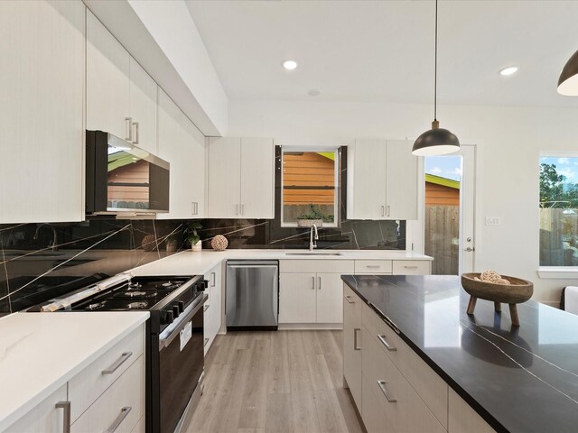 kitchen with dishwasher, gas stove, sink, hanging light fixtures, and white cabinets