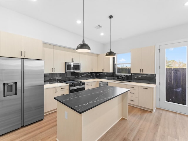 kitchen with light hardwood / wood-style floors, stainless steel appliances, decorative backsplash, a kitchen island, and pendant lighting