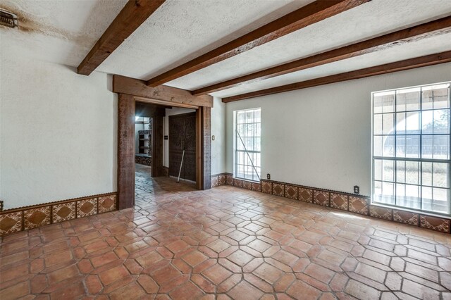 spare room with beam ceiling and a textured ceiling