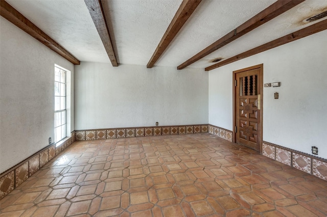 empty room with beamed ceiling and a textured ceiling