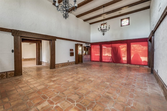 unfurnished living room featuring beamed ceiling, a notable chandelier, and a high ceiling