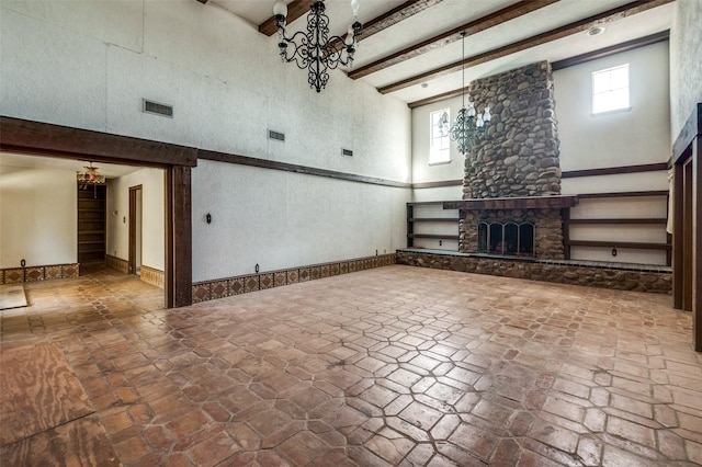 unfurnished living room with a fireplace, beamed ceiling, a chandelier, and a high ceiling