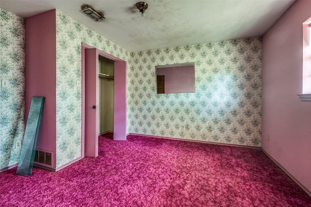 carpeted empty room with a textured ceiling