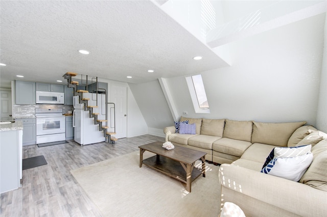 living room featuring a skylight, light hardwood / wood-style flooring, and a textured ceiling