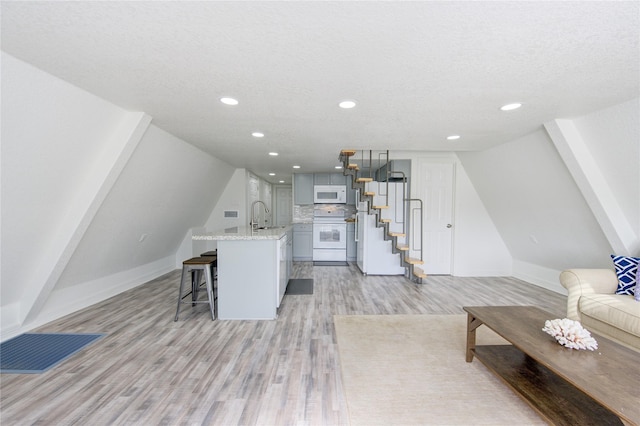 kitchen featuring sink, light hardwood / wood-style flooring, stove, a kitchen bar, and a center island with sink