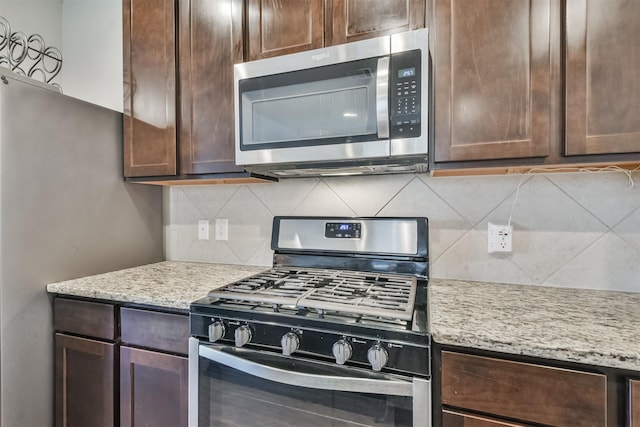 kitchen with stainless steel appliances, light stone counters, and tasteful backsplash