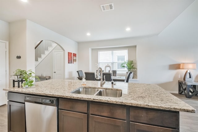 kitchen with sink, stainless steel dishwasher, light stone countertops, light hardwood / wood-style floors, and dark brown cabinetry