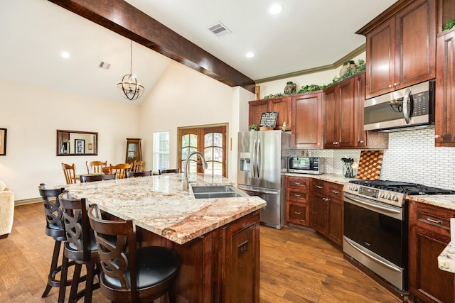 kitchen with beamed ceiling, dark hardwood / wood-style floors, a center island with sink, and stainless steel appliances