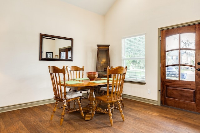 dining area featuring wood-type flooring and vaulted ceiling