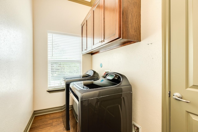 laundry area with hardwood / wood-style flooring, cabinets, and washing machine and clothes dryer