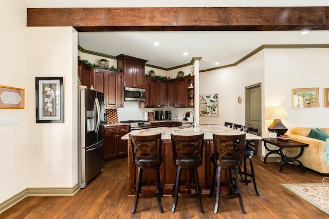 kitchen featuring dark hardwood / wood-style floors, stainless steel appliances, a breakfast bar, and an island with sink