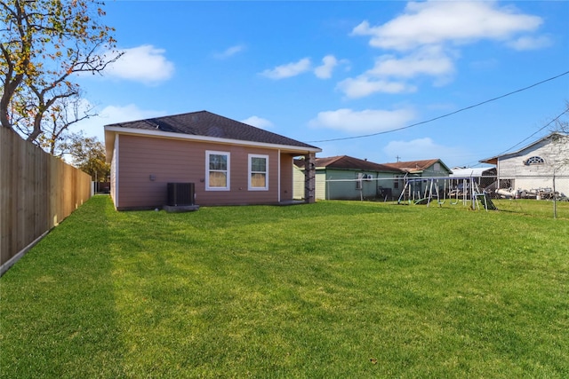 rear view of property featuring a playground, a yard, and central air condition unit