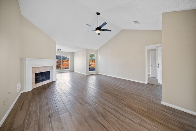 unfurnished living room with ceiling fan, lofted ceiling, a textured ceiling, and a tiled fireplace