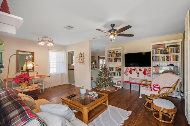 living room featuring ceiling fan with notable chandelier and dark hardwood / wood-style flooring