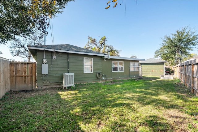 rear view of property with a lawn and central air condition unit