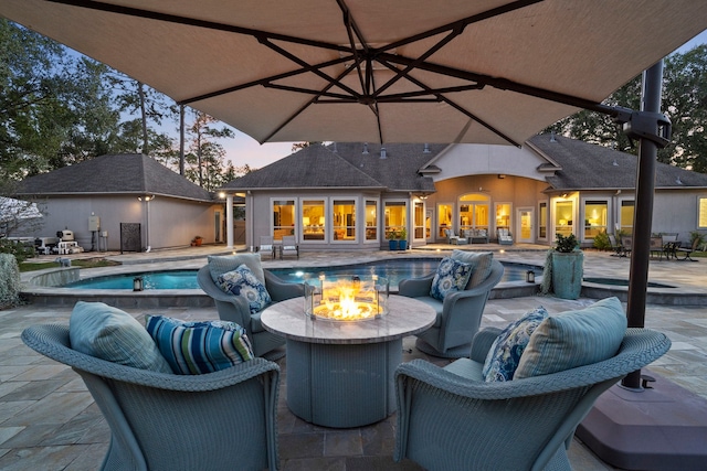 pool at dusk featuring a patio and an outdoor living space with a fire pit