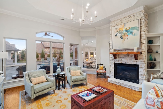 living room featuring hardwood / wood-style flooring, crown molding, a fireplace, and an inviting chandelier