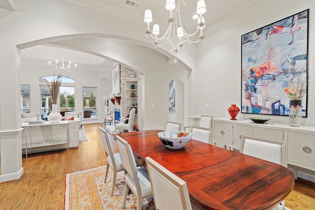 dining area with a notable chandelier, crown molding, and light hardwood / wood-style floors