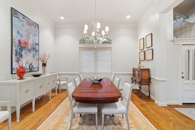 dining room with an inviting chandelier, ornamental molding, and light wood-type flooring