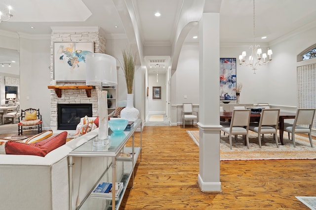 living room featuring crown molding, a stone fireplace, and light hardwood / wood-style flooring